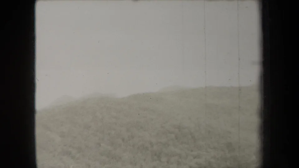 1938 New York 8mm frame of a soft, misted countryside slope with distant hills and visible grain.