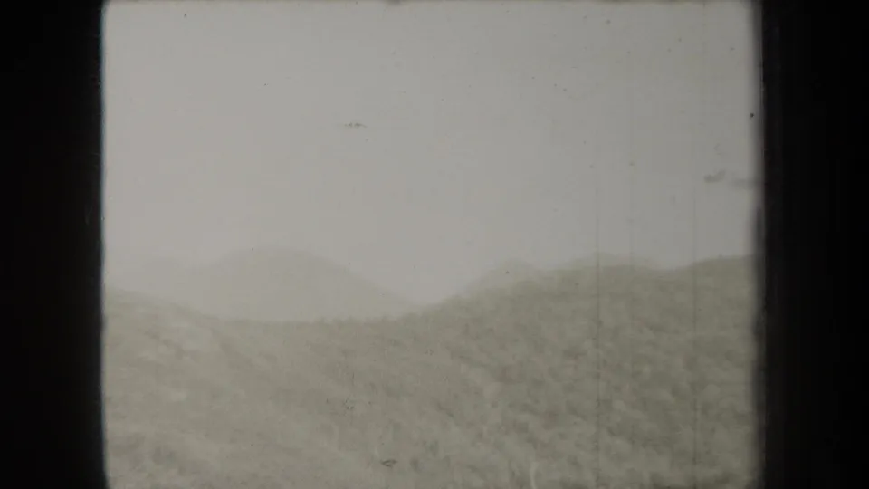 1938 New York 8mm frame showing a mist-softened hill line under an overcast sky, with dark edge borders and light surface wear.