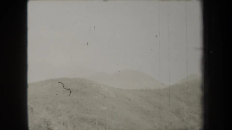 1938 New York 8mm frame showing a hazy mountain ridge, pale sky, wooded slope, and visible film borders.