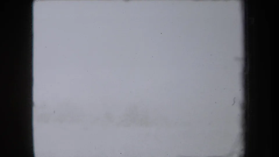 Pale end frame from the 8mm scan with minimal visible subject detail, faint dust, and dark frame edges.