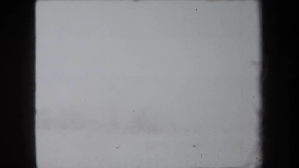 A washed-out 8mm frame from the New York home-movie clip, with little visible subject detail beyond film borders and surface dust.