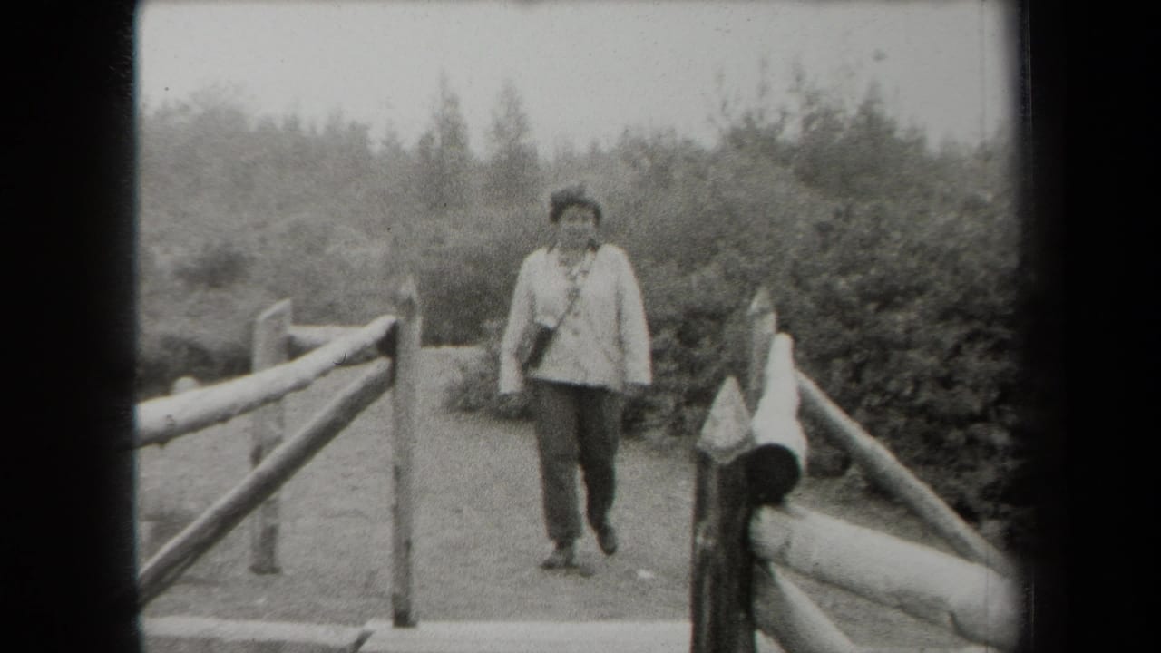 Adult woman walks toward camera on a rustic wooden bridge with trees behind her.