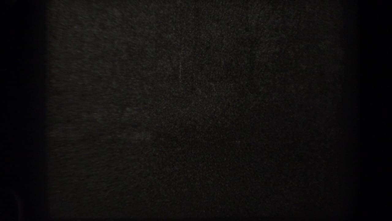 Very dark 8mm frame from the 1938 New York clip, showing mostly film grain and shadow with no clearly readable figures.