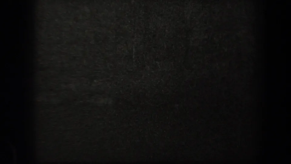 Very dark 8mm frame from the 1938 New York clip, showing mostly film grain and shadow with no clearly readable figures.