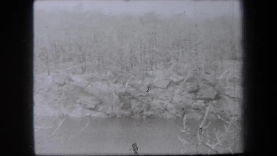 1938 New York 8mm landscape frame with a rocky treeline and pale foreground, softened by exposure and film wear.
