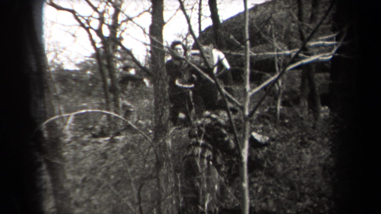 In 1938 New York home-movie footage, hikers in coats and hats appear among bare branches on a wooded slope.