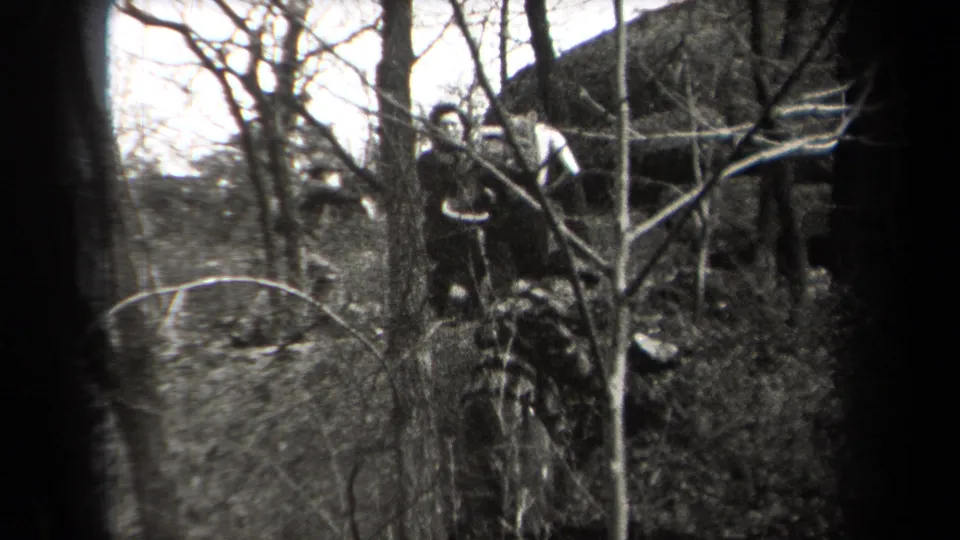 In 1938 New York home-movie footage, hikers in coats and hats appear among bare branches on a wooded slope.