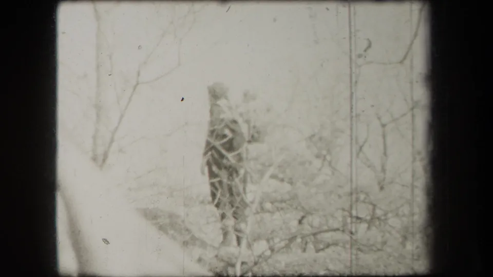 A distant person walks through a bare wooded New York landscape in 1938 8mm home-movie footage.
