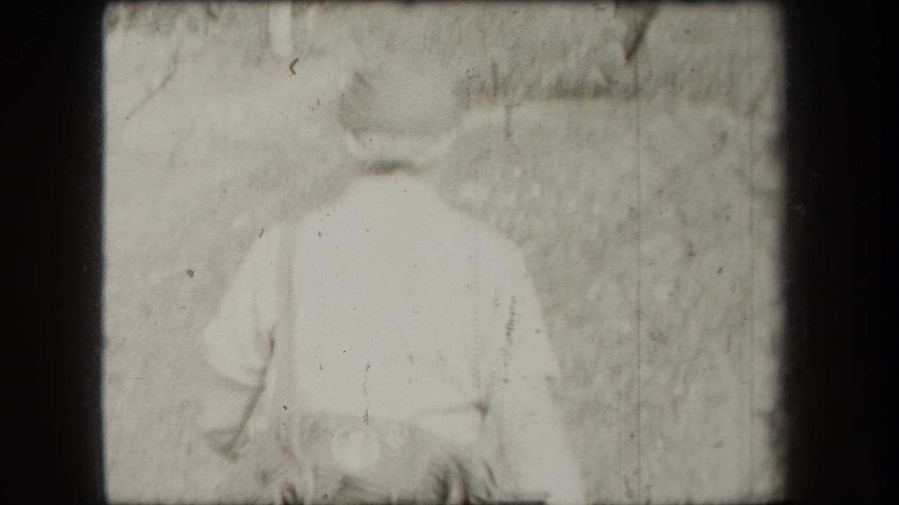1938 New York 8mm frame showing a hiker from behind on a wooded trail, softly exposed and partially obscured by film wear.