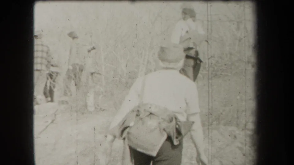 A small hiking group in period clothing follows a brushy trail in 1938 New York home-movie footage.