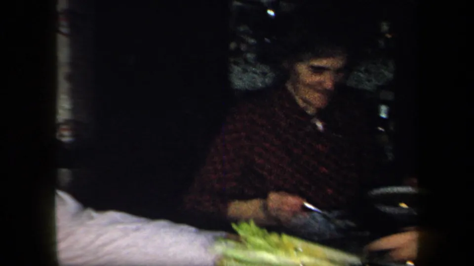 1958 New York home interior showing a woman seated at dinner with a bowl, tableware, and food on the table.