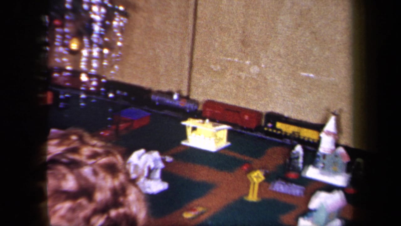 Toy train layout with miniature buildings and a child’s head near the lower edge.