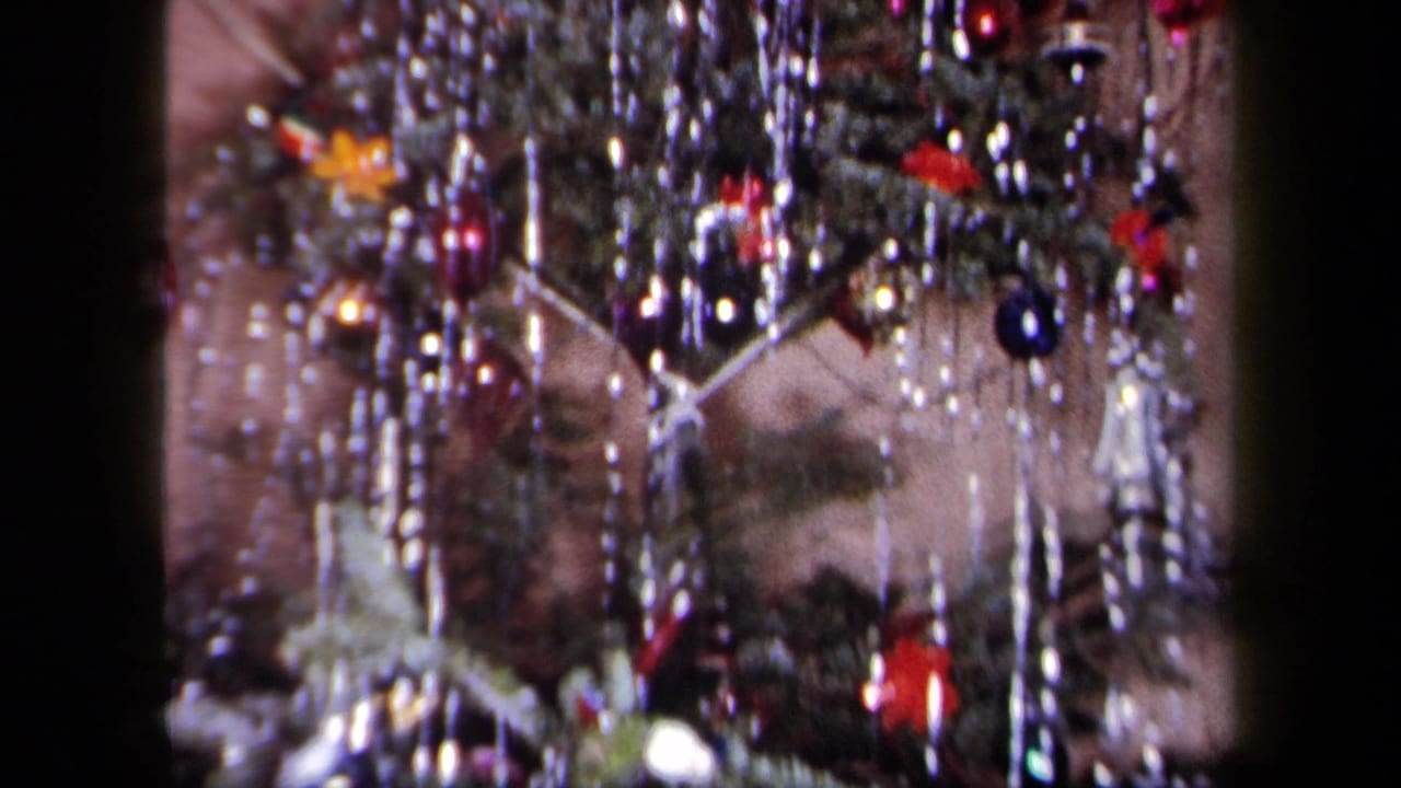 Decorated Christmas tree branches with tinsel, ornaments, and small figures.