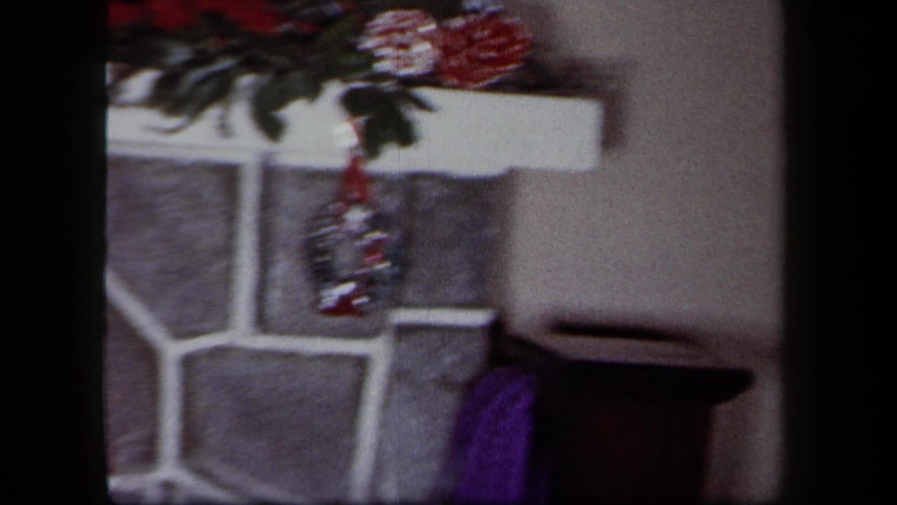 1958 New York home-movie frame showing a stone fireplace area with Christmas decorations and a red stocking.