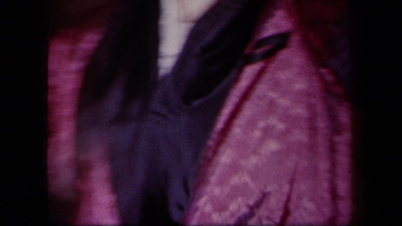 Close, blurred view of pink clothing and a dark jacket during indoor dancing.