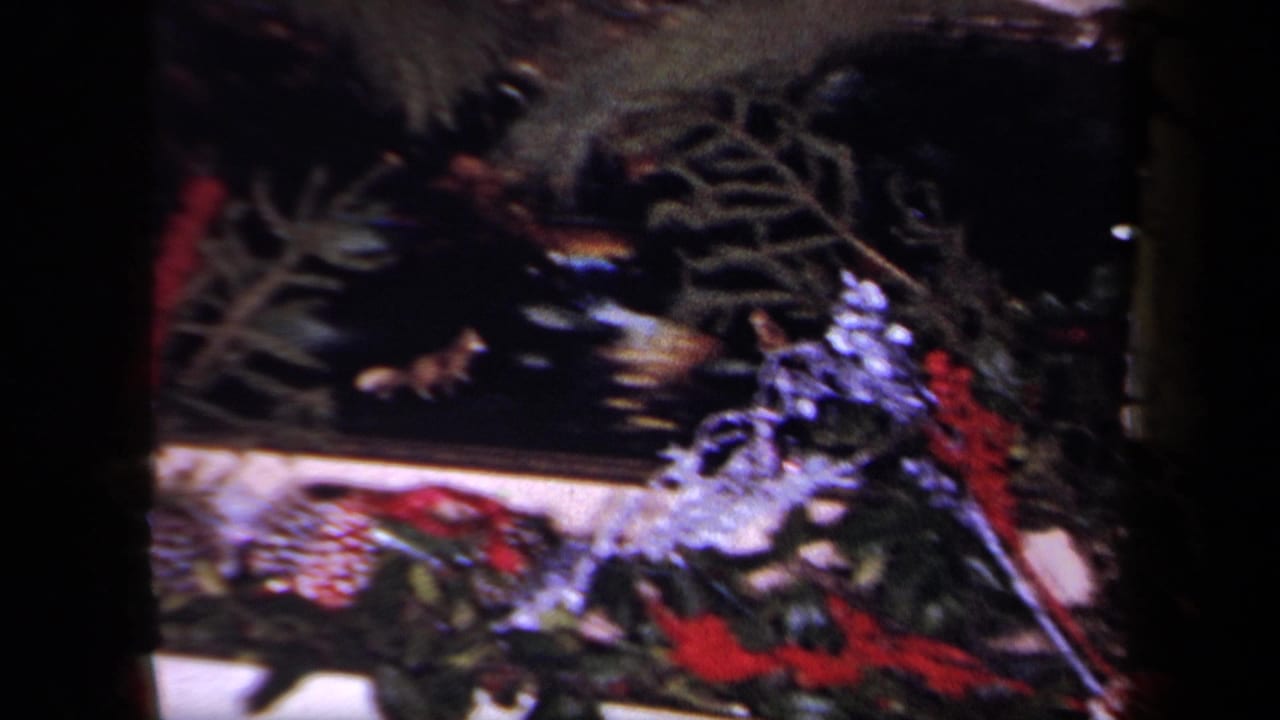 Close view of Christmas garland, red ribbon, pinecones, and dark mantel area.