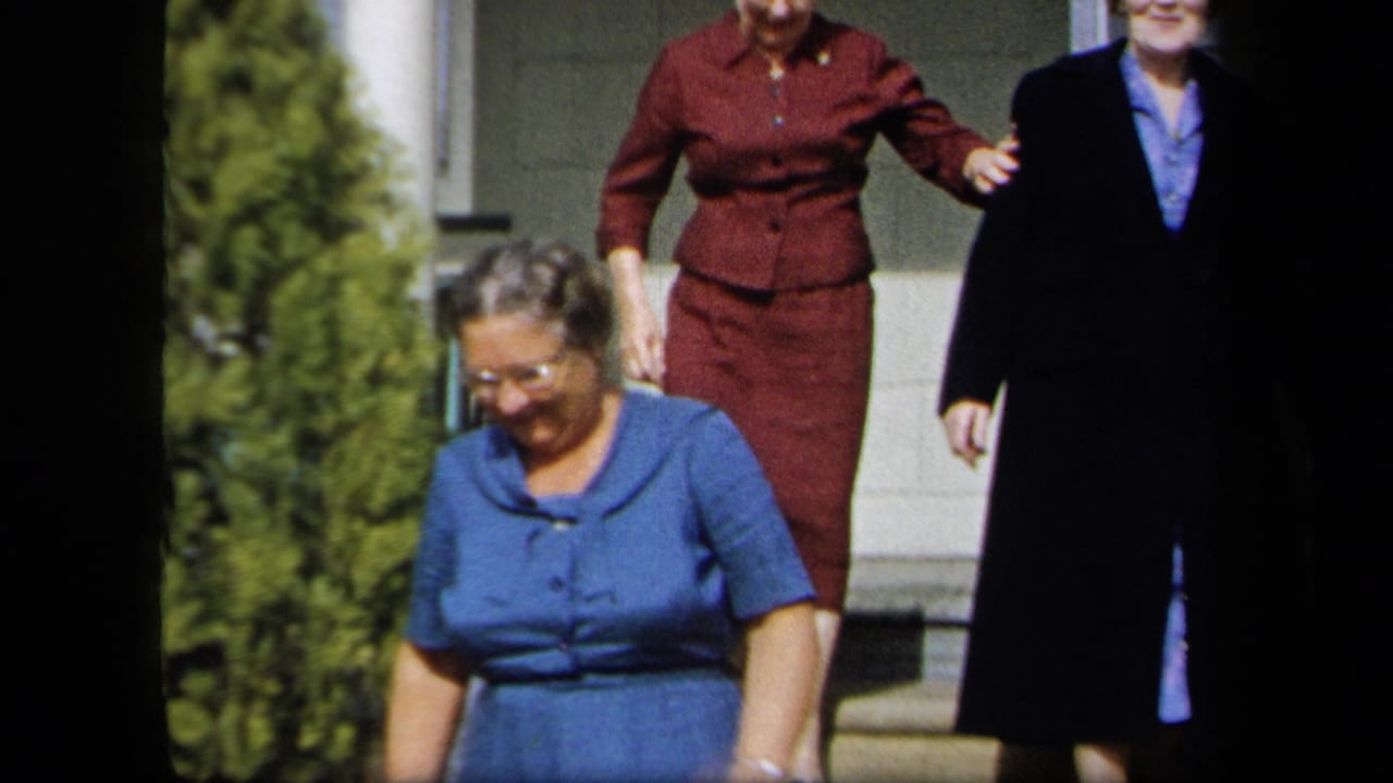 Women in formal dresses and coats descend exterior steps in bright daylight.