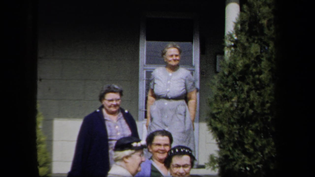 Adult women in 1950s dress gather outside a New York residence, some standing on porch steps and others partly framed below.