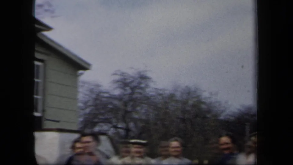 The final frame shows women near a residential house and leafless trees, with motion blur from the handheld 8mm camera.