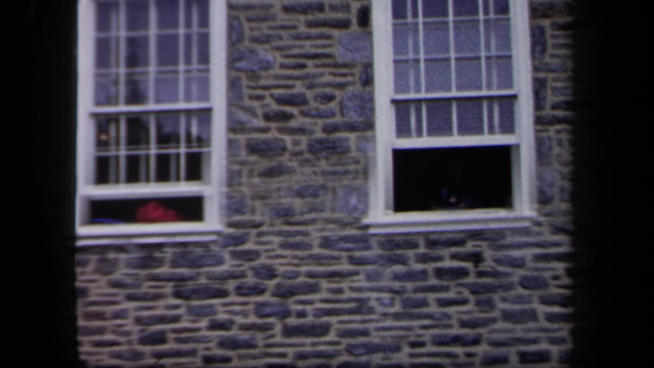 Stone building facade with two white-framed windows and open lower sashes.