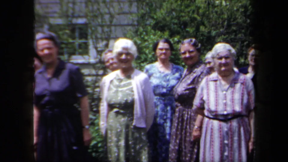 End frame from the 1958 New York garden gathering, showing older women in patterned dresses and cardigans facing the camera.