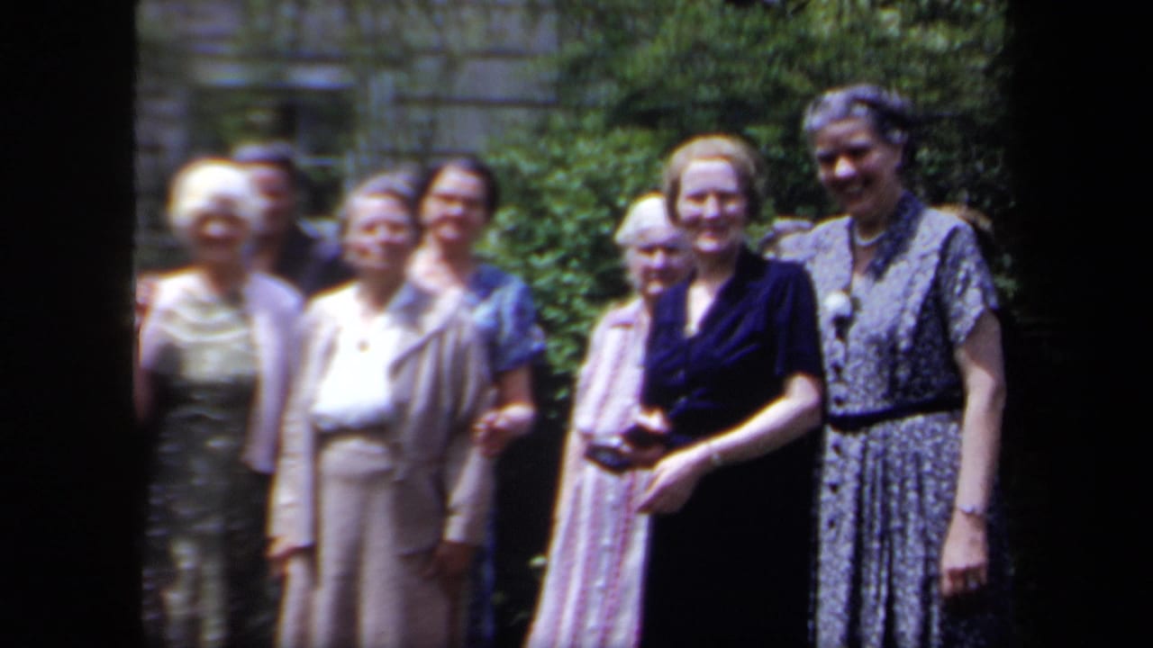 In 1958 New York home-movie footage, older women in dresses gather in a garden and look toward the camera.