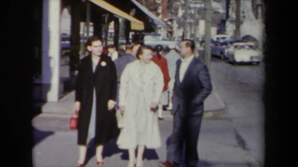 The group advances along a New York sidewalk, with mid-century cars and pedestrians visible in the background.
