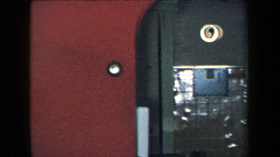 1959 New York 8mm frame showing a closed elevator doorway, red wall, round lights, and dim interior reflections.