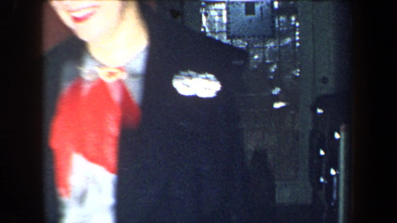 Close cropped woman in red scarf and dark coat smiles near a doorway.