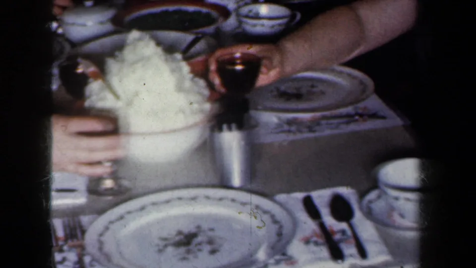 1959 New York home-movie close-up of tableware, drinks, and hands around a formal dinner setting.