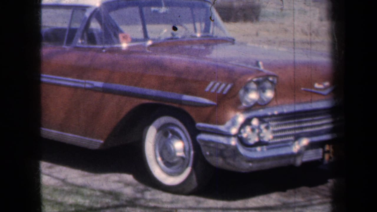 Red Chevrolet convertible viewed from the side front, with chrome trim and whitewall tire visible.