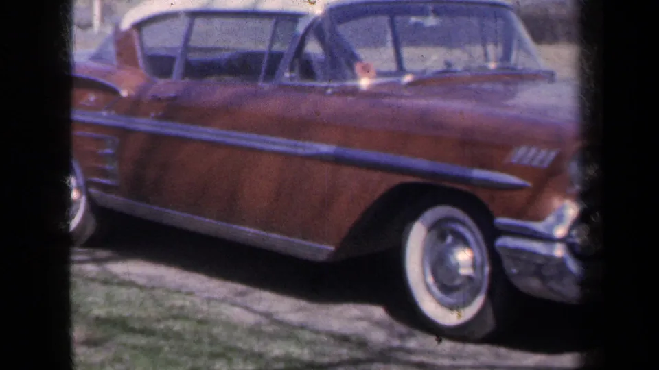 The red 1959 Chevrolet convertible is framed in a wider side view, with long chrome trim, windshield, rear side window area, and front whitewall tire.