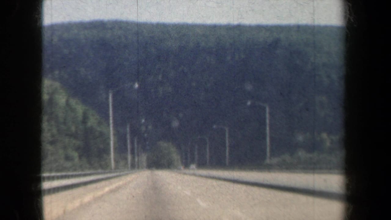 1959 New York 8mm view from a moving car on a divided freeway through forested hills.