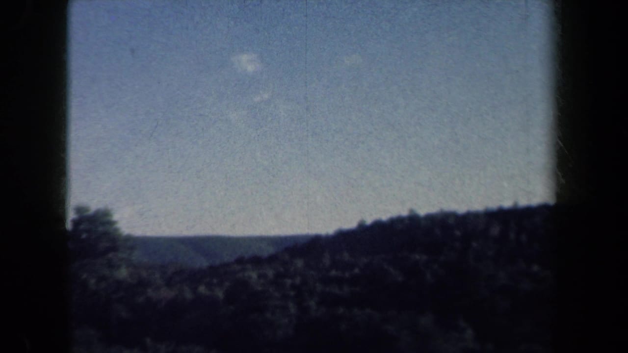 1959 rural New York home-movie view of distant wooded hills and blue sky from a moving vehicle.