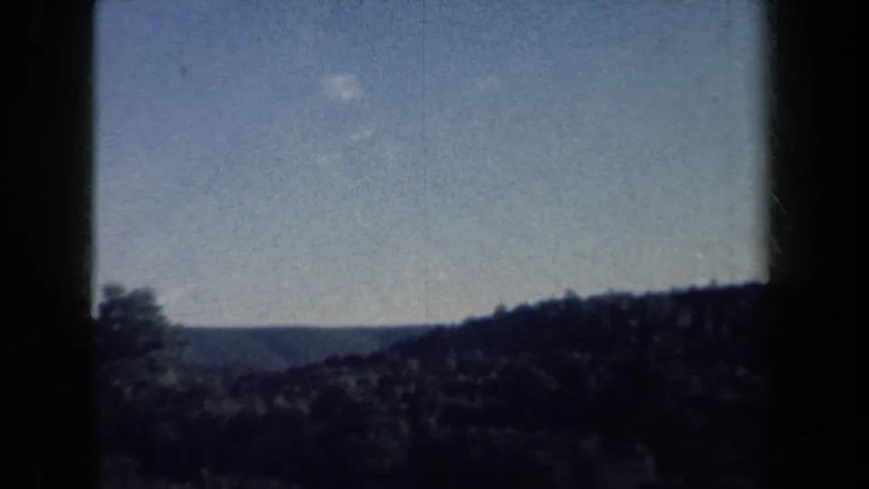1959 rural New York home-movie view of distant wooded hills and blue sky from a moving vehicle.
