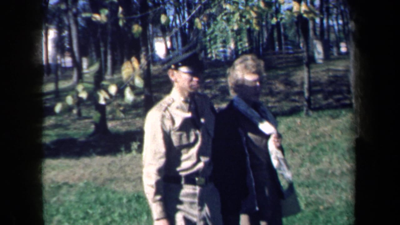 The couple moves closer to the camera in a New York park, with the man in a light service uniform and cap.