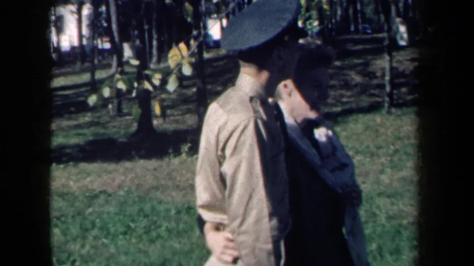The woman looks down as she walks close to the uniformed man in soft-focus 1959 New York home-movie footage.