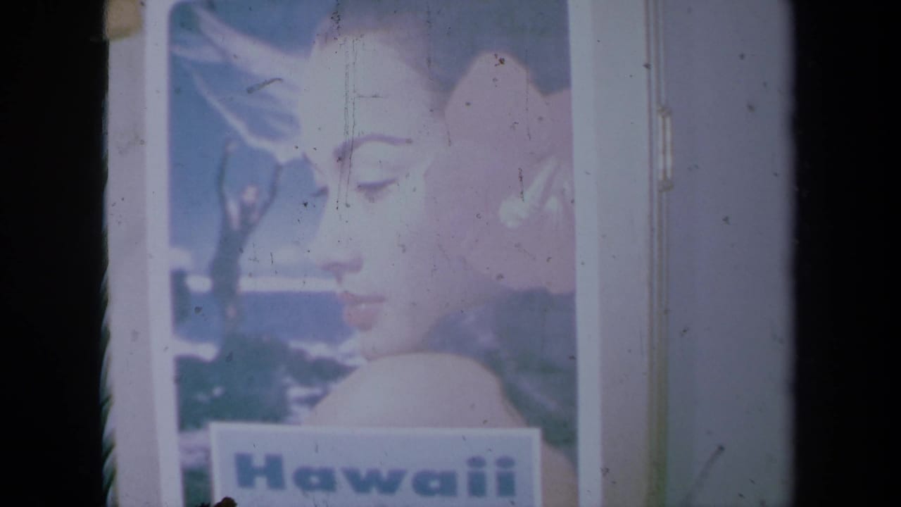 1961 California 8mm frame showing a printed Hawaii poster with a woman's profile, flower, and visible poster border.
