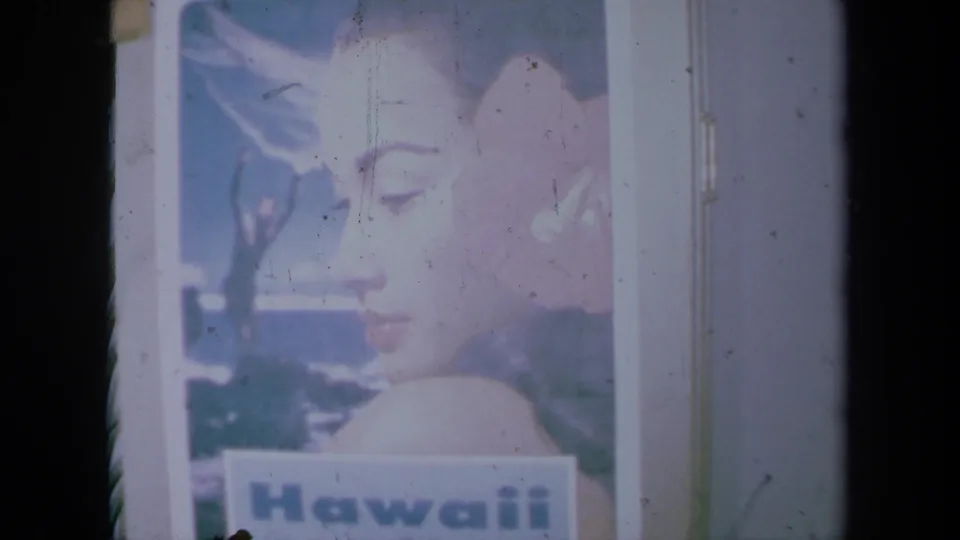 1961 California 8mm frame showing a printed Hawaii poster with a woman's profile, flower, and visible poster border.