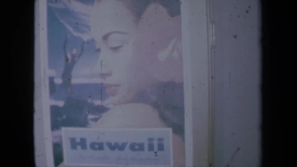 1961 California 8mm frame of a Hawaii poster on a wall, with a woman's profile, flower, and visible film scratches.