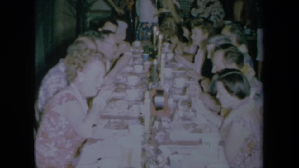 Guests dine at a long candlelit table inside a private California home or venue during the 1961 Hawaiian-themed gathering.