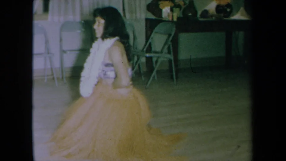 The adult dancer appears lower in the frame during a hula movement, filmed inside a private California room in 1961.