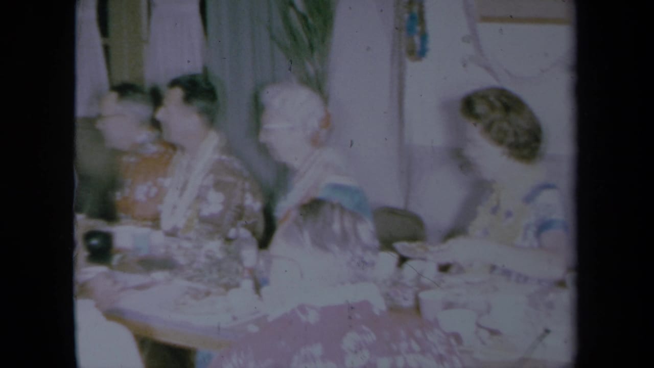 Older adults in floral shirts seated around a table in a private room.