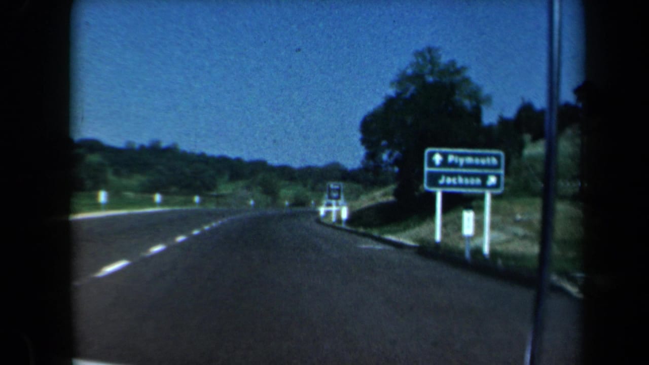 Car-view highway scene with a green sign for Plymouth and Jackson beside the road.