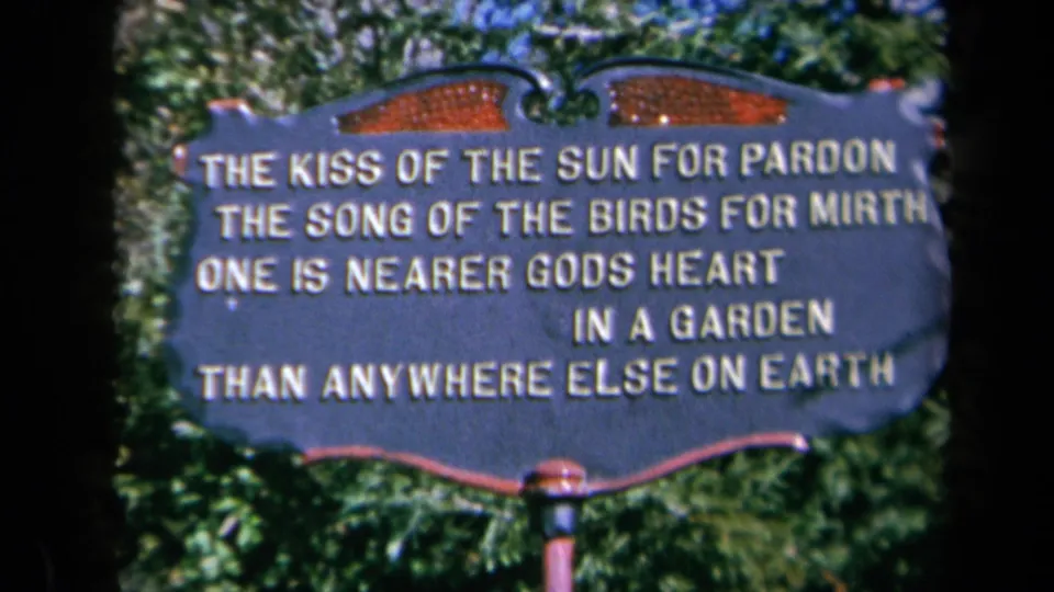 1969 California 8mm close-up of the garden sign text, with soft focus, saturated color, and leafy background.
