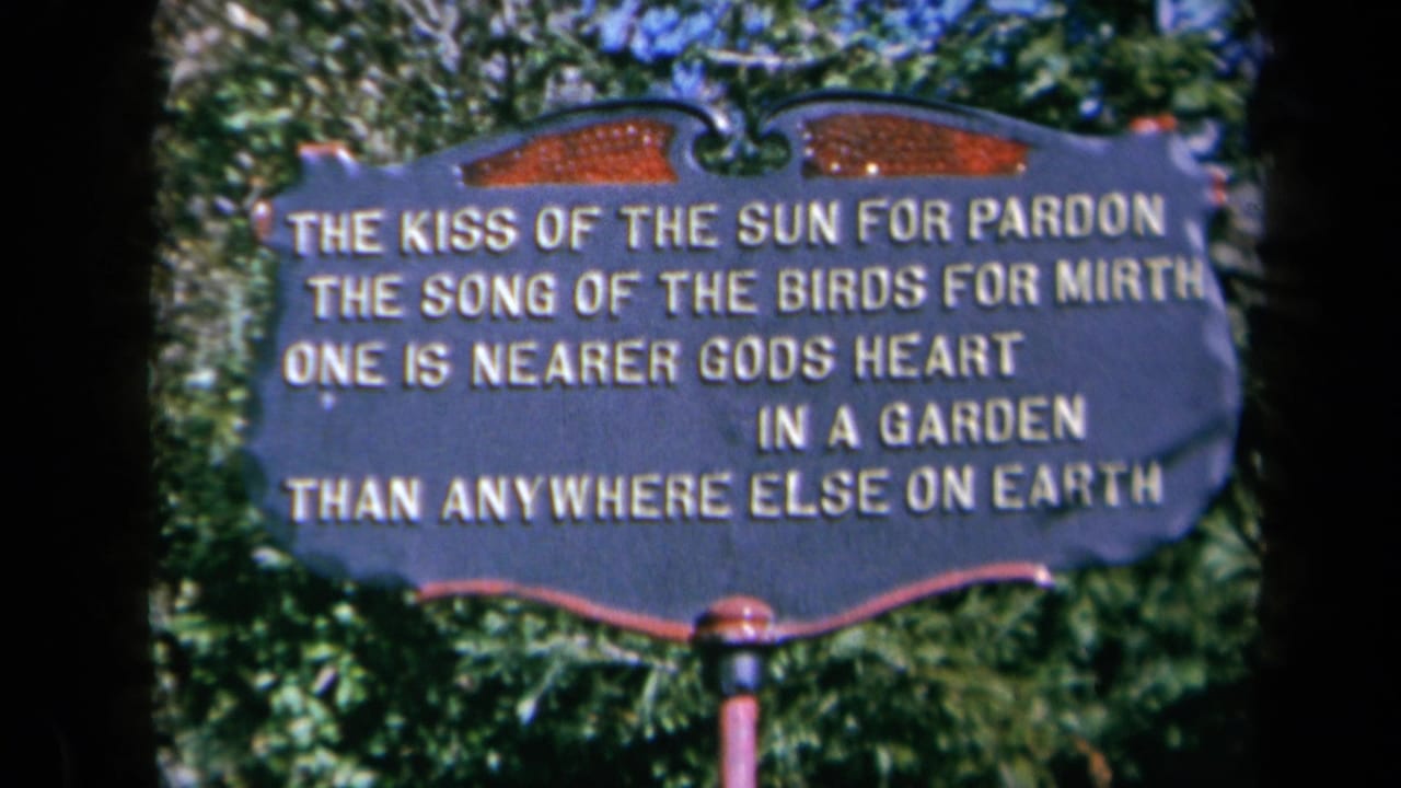 1969 California 8mm frame showing a decorative garden sign with a religious garden verse, surrounded by leafy greenery.