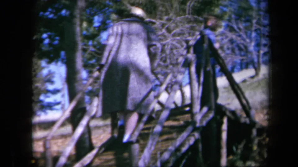 A closer 8mm frame shows the person from behind on garden steps, with tree branches and a low structure nearby.