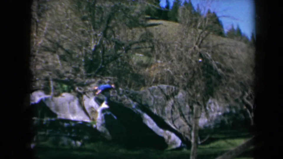 1969 California 8mm frame showing a child mid-air beside rocks, captured during an outdoor flip.