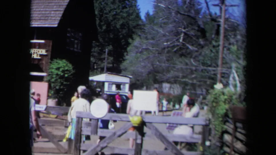 Handheld 8mm frame of visitors walking by fencing and signage at Daffodil Hill in California.