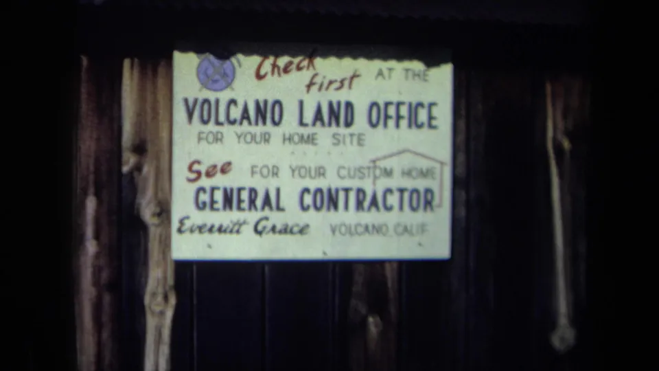1969 California 8mm frame showing the Volcano Land Office sign with general contractor text and the name Everitt Grace.
